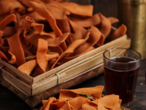 Ribbon pakoda in a wooden tray with a glass of tea