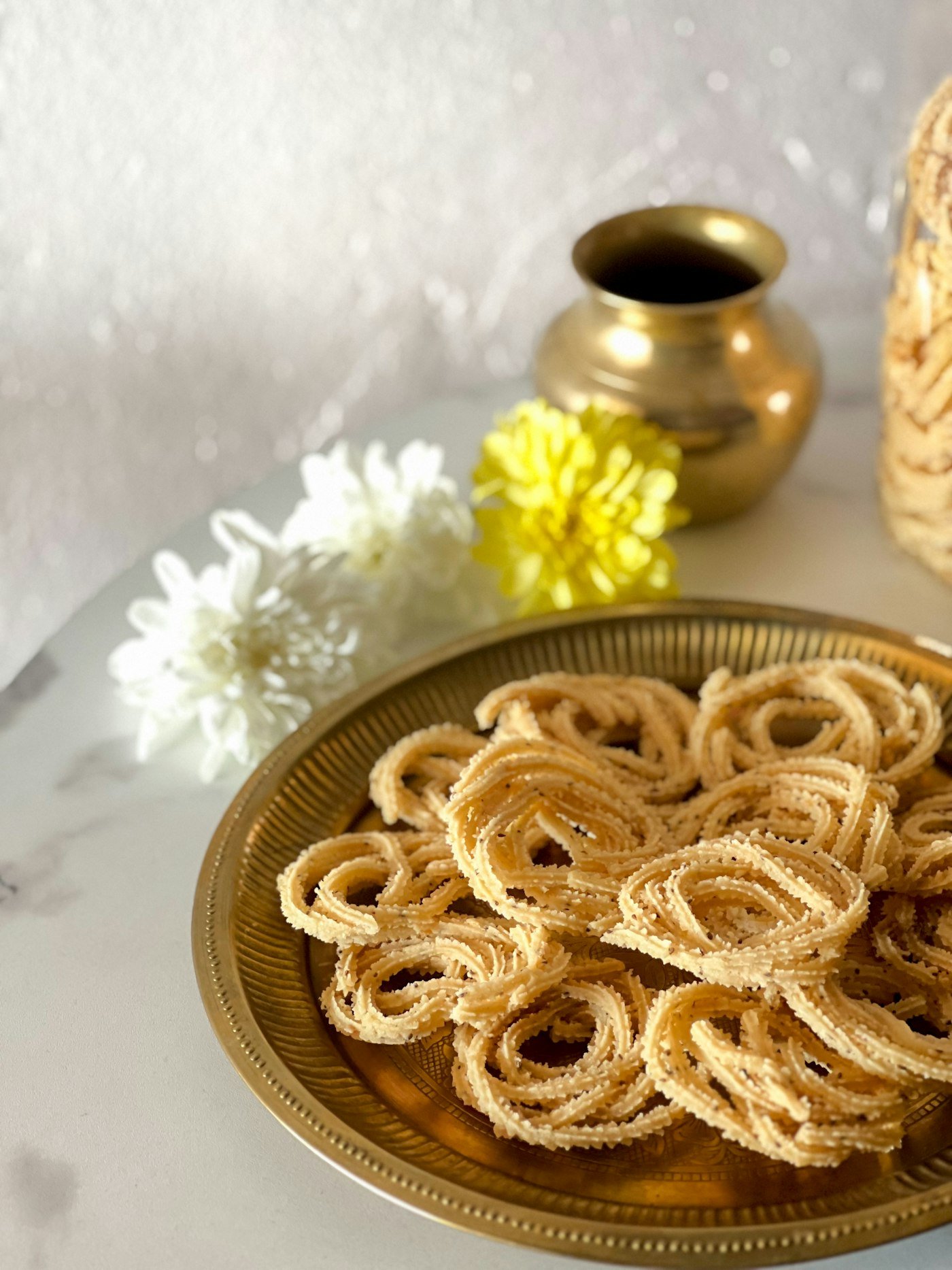Murukku served on a brass plate with flowers