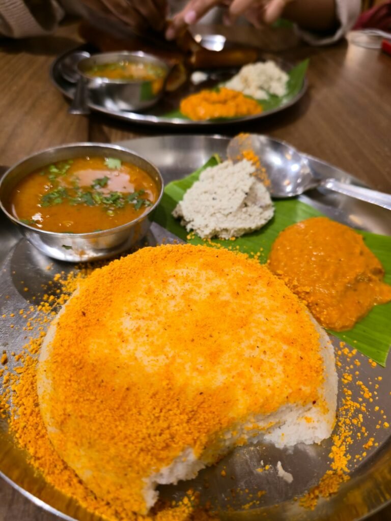 Idli topped with podi, with chutney and sambar